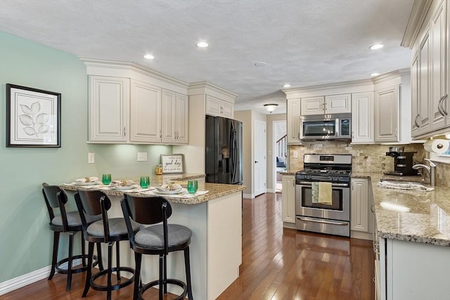 kitchen with appliances with stainless steel finishes, white cabinetry, sink, backsplash, and dark wood-type flooring