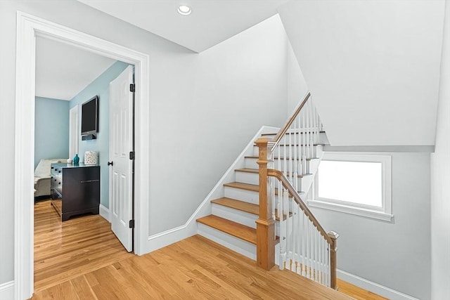 stairs with baseboards, wood finished floors, and recessed lighting
