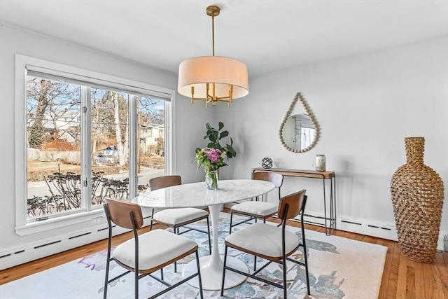 dining space featuring a baseboard radiator and wood finished floors