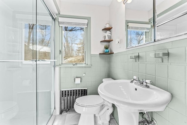 full bath with radiator, a sink, a shower stall, and toilet