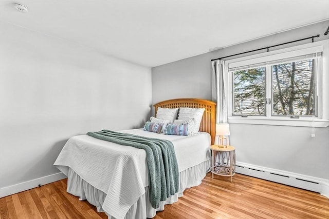 bedroom featuring baseboard heating, wood finished floors, and baseboards