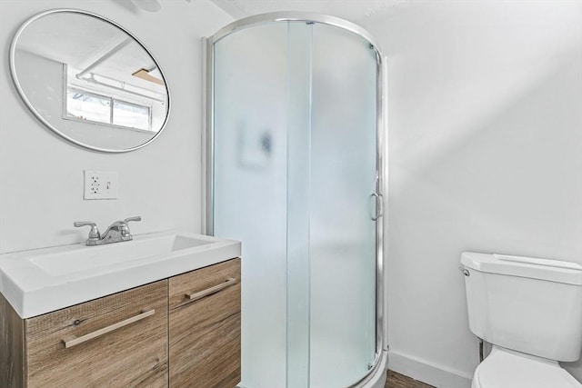 bathroom with baseboards, a shower stall, toilet, and vanity