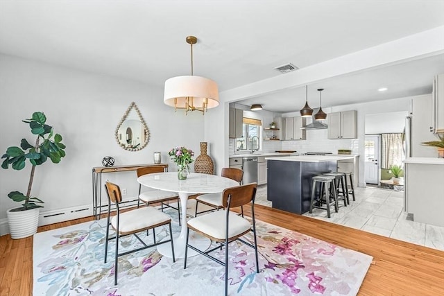 dining room with light wood-style flooring, baseboard heating, and visible vents