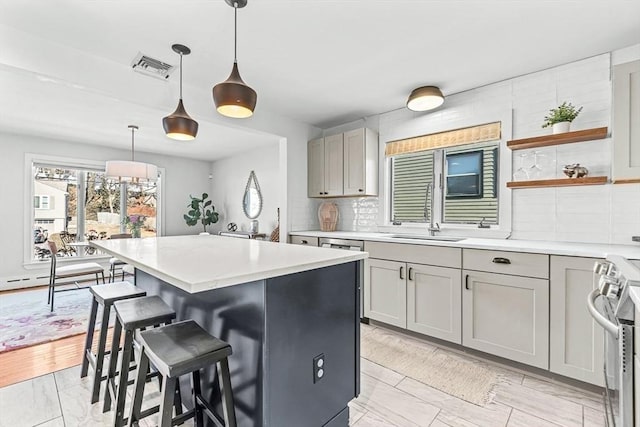 kitchen featuring a kitchen island, a sink, backsplash, range, and a kitchen bar