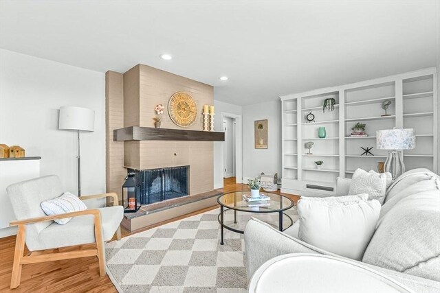 living room with a brick fireplace, wood finished floors, and recessed lighting