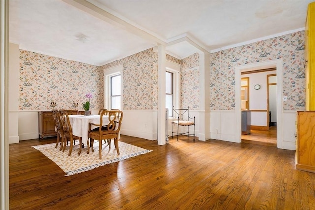 dining space with wood finished floors, wainscoting, and wallpapered walls