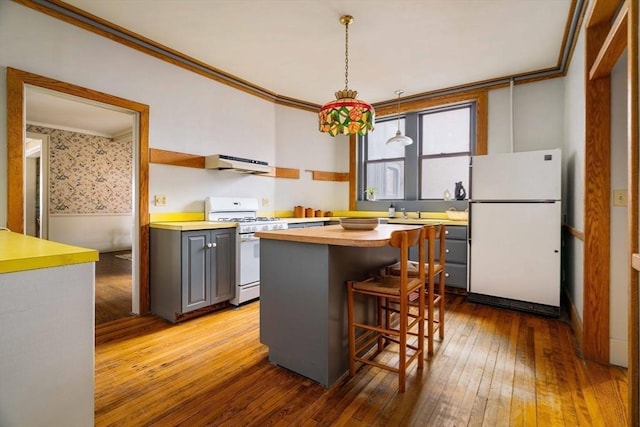 kitchen featuring under cabinet range hood, white appliances, gray cabinets, and crown molding