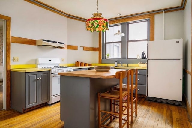 kitchen with under cabinet range hood, a kitchen island, white appliances, butcher block counters, and crown molding