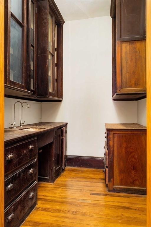 bar featuring light wood-style floors, baseboards, and a sink