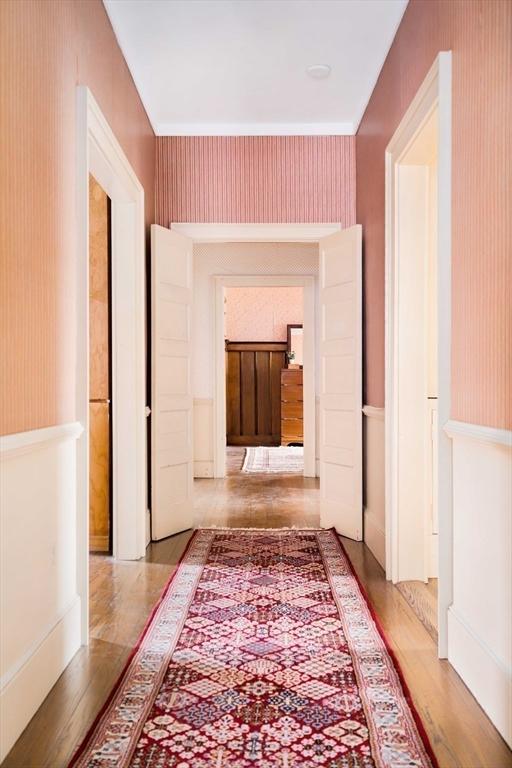 hall with wood finished floors and wallpapered walls