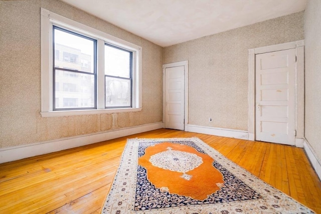 spare room with baseboards and hardwood / wood-style floors