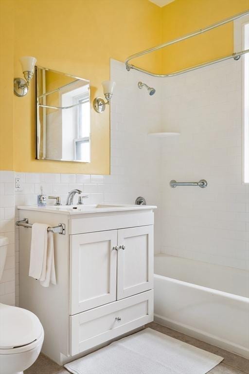 full bath featuring vanity, toilet, tile walls, and bathtub / shower combination