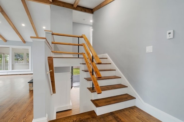 stairway featuring wood-type flooring, beam ceiling, and a baseboard heating unit