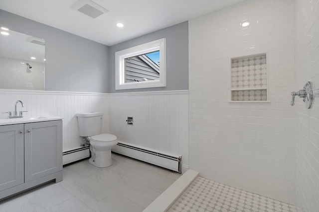 bathroom with vanity, toilet, baseboard heating, and a tile shower