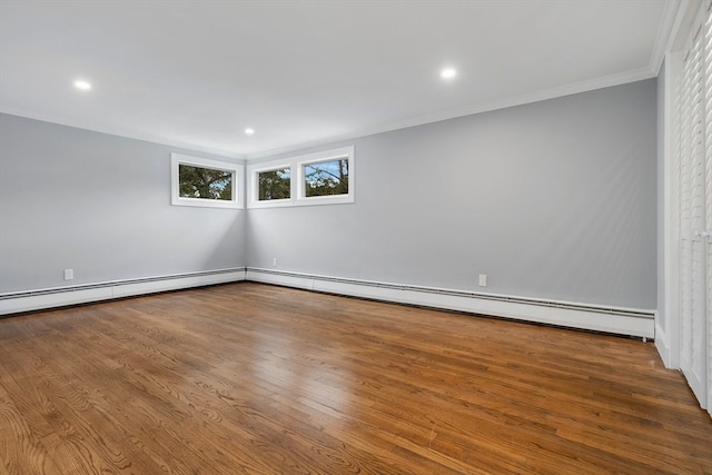 spare room featuring ornamental molding, a baseboard heating unit, and hardwood / wood-style floors