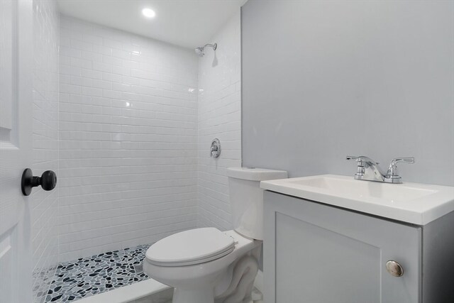 bathroom featuring vanity, toilet, and tiled shower