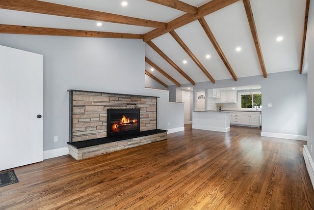 unfurnished living room featuring a baseboard heating unit, beamed ceiling, dark hardwood / wood-style floors, high vaulted ceiling, and a stone fireplace