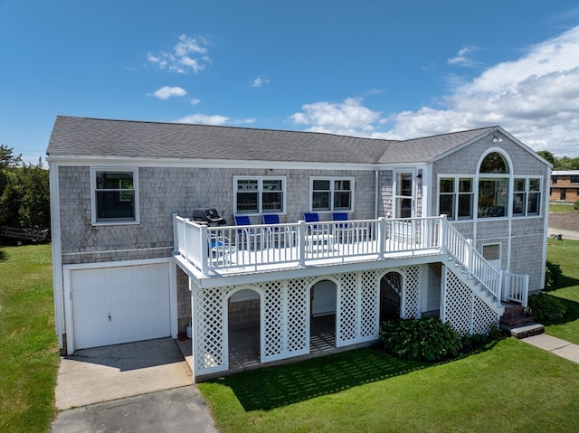 rear view of house featuring a garage, a wooden deck, and a lawn