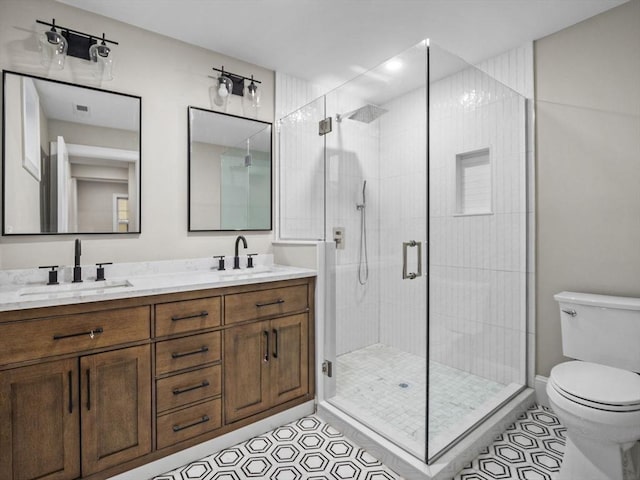 bathroom featuring tile patterned floors, vanity, toilet, and a shower with shower door