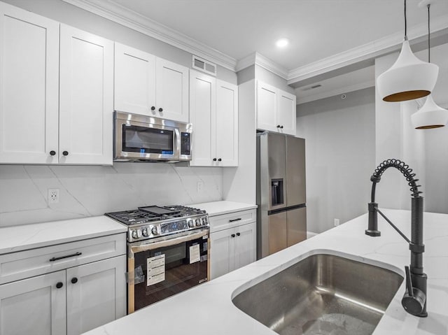 kitchen with pendant lighting, white cabinets, sink, decorative backsplash, and appliances with stainless steel finishes