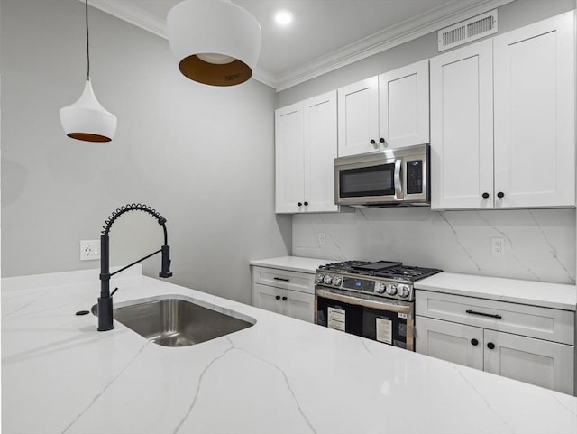 kitchen with sink, white cabinets, stainless steel appliances, and decorative light fixtures