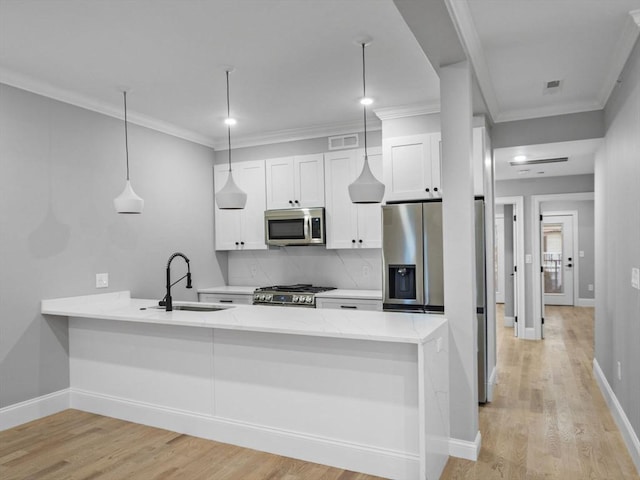 kitchen with white cabinets, sink, hanging light fixtures, light hardwood / wood-style floors, and stainless steel appliances