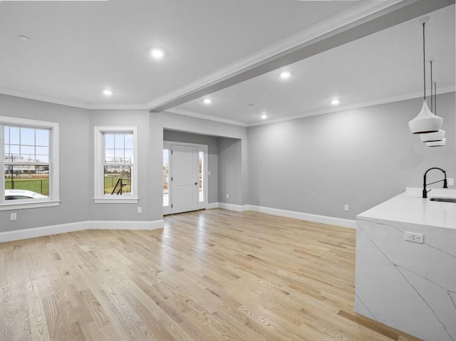 living room featuring sink, light wood-type flooring, and ornamental molding