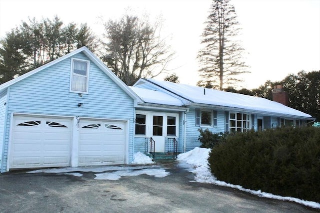 view of front of property featuring a garage, driveway, and a chimney