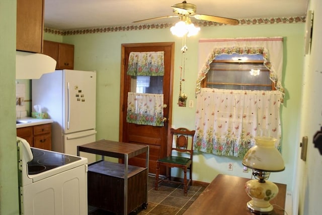 kitchen featuring ceiling fan, white appliances, dark tile patterned floors, baseboards, and extractor fan