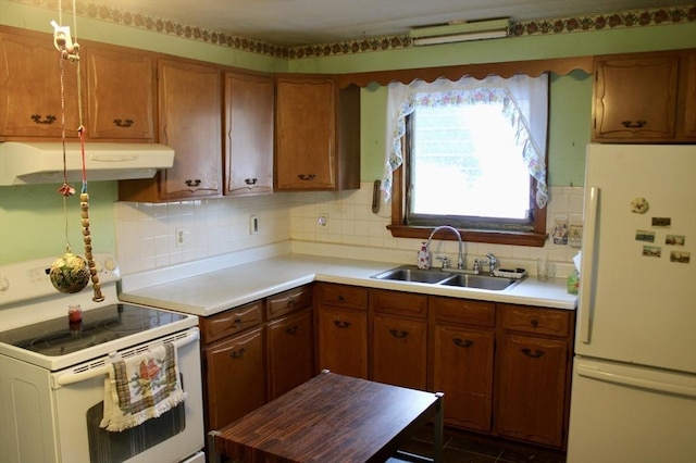 kitchen with light countertops, brown cabinetry, a sink, white appliances, and under cabinet range hood