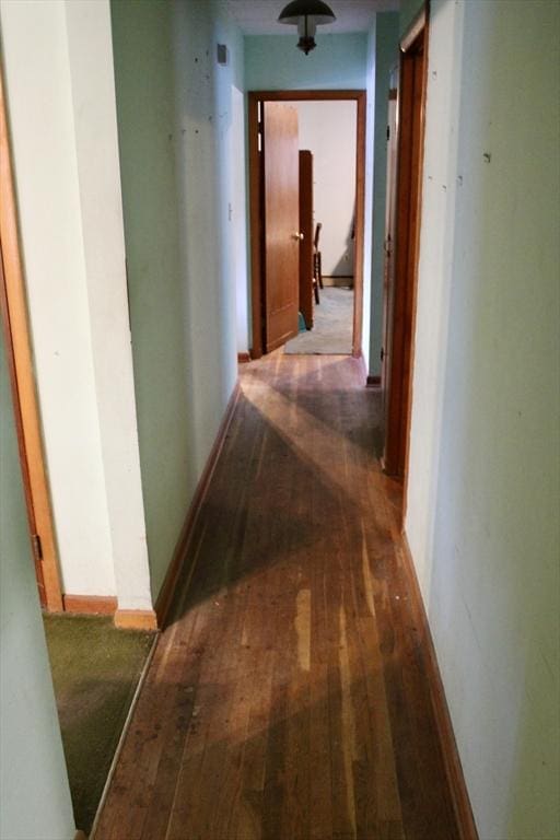 corridor featuring baseboards and hardwood / wood-style flooring