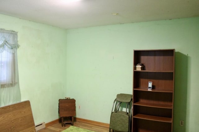 unfurnished room featuring baseboards, a baseboard heating unit, and wood finished floors