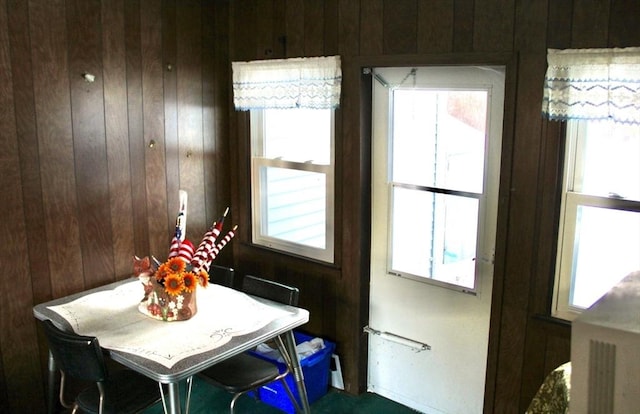 dining space featuring a healthy amount of sunlight and wooden walls