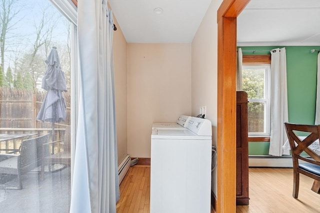 clothes washing area with separate washer and dryer, laundry area, wood finished floors, and a baseboard heating unit