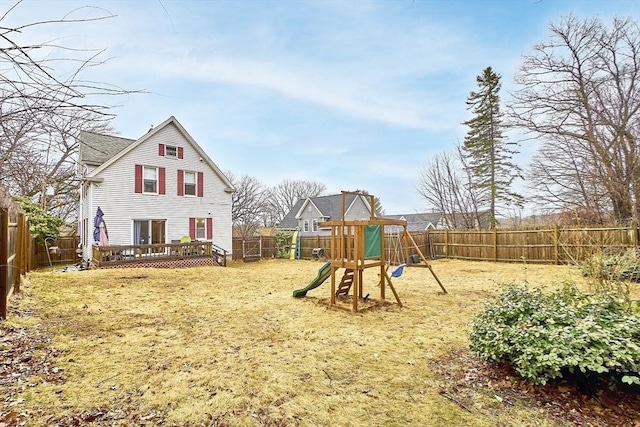 view of jungle gym featuring a yard, a deck, and a fenced backyard