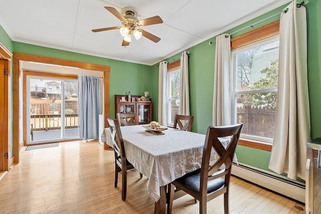 dining area with crown molding, light wood-type flooring, baseboard heating, and ceiling fan