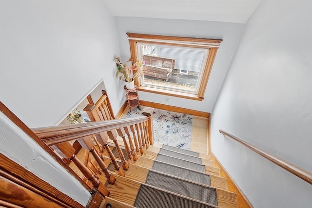 staircase with a wealth of natural light, wood finished floors, and baseboards