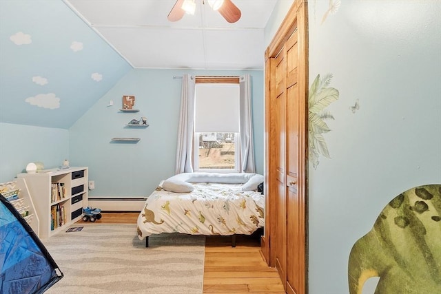 bedroom with light wood finished floors, lofted ceiling, ceiling fan, and baseboard heating