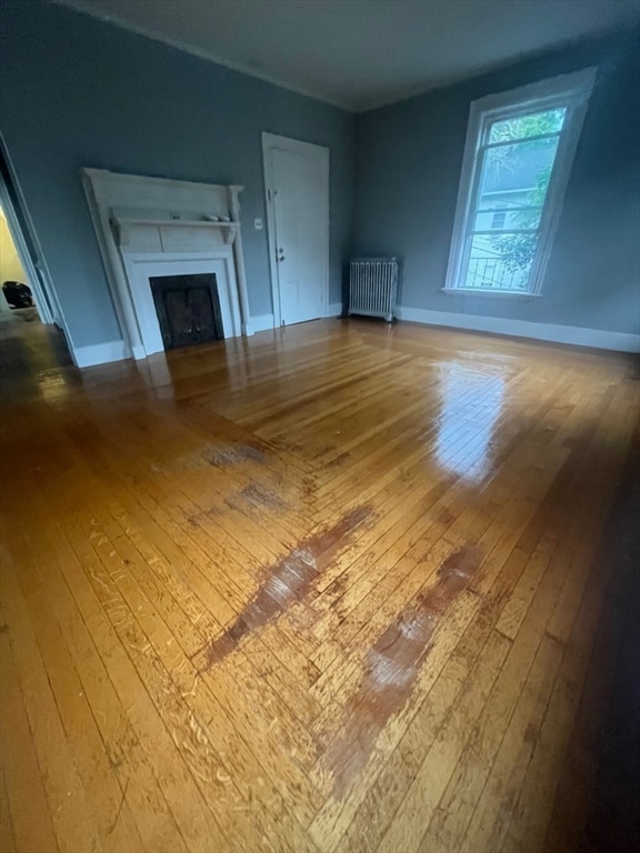 unfurnished living room with wood-type flooring and radiator