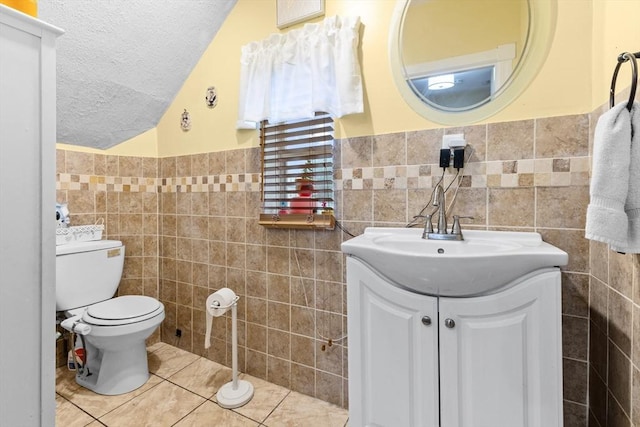 39 Crapo St, New Bedford, MA 02740 - half bathroom featuring tile walls, vanity, tile patterned flooring, a textured ceiling, and lofted ceiling