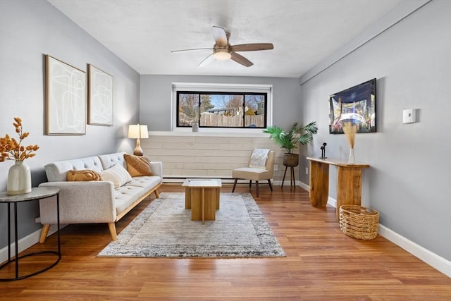 living area featuring wood finished floors, a ceiling fan, and baseboards