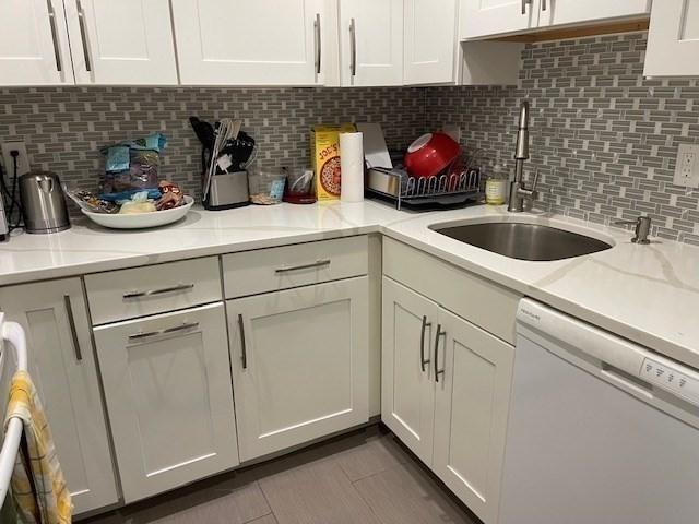 51 John St Unit 201, Brookline, MA 02446 - kitchen with white dishwasher, white cabinets, tasteful backsplash, light countertops, and tile patterned floors
