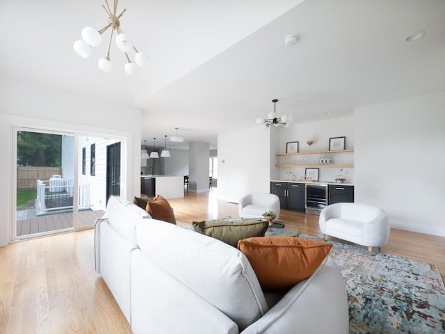 living room featuring bar area, a notable chandelier, and light hardwood / wood-style flooring