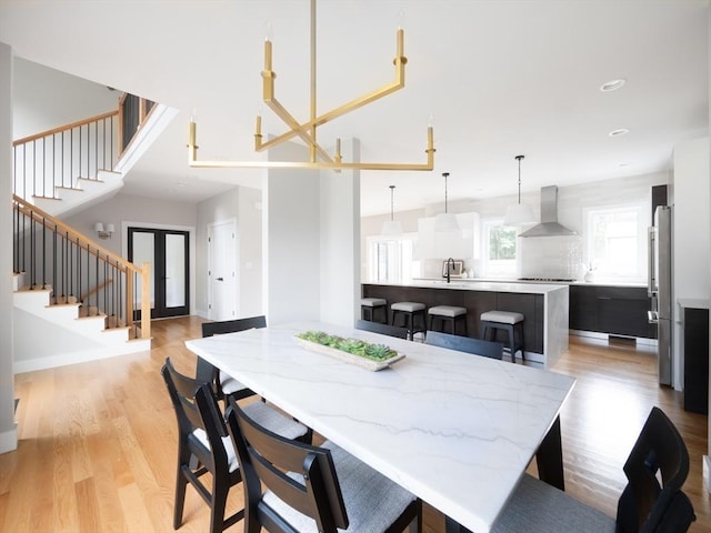 dining space featuring french doors, sink, and light wood-type flooring