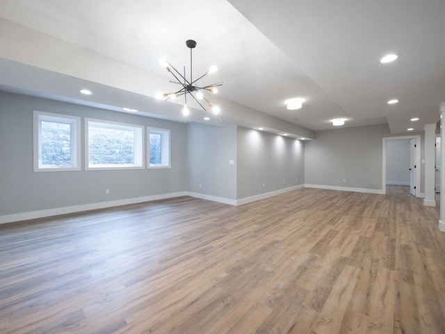 unfurnished room with a notable chandelier and light wood-type flooring