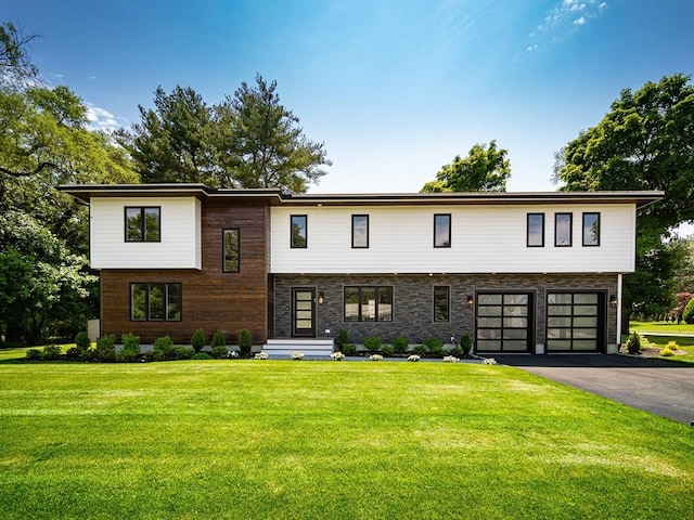 raised ranch featuring a garage and a front lawn