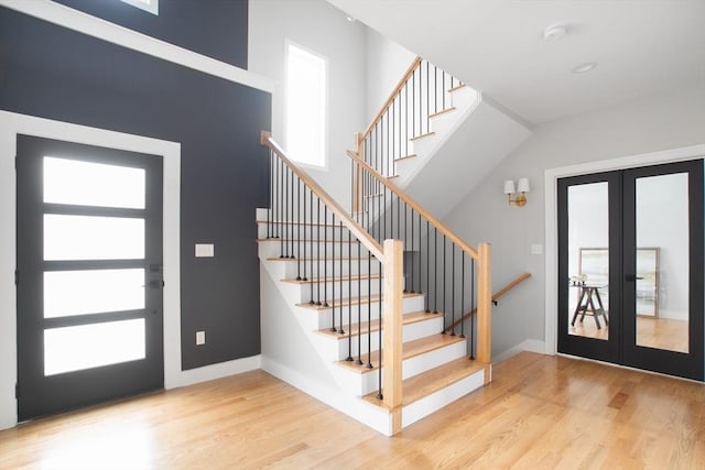 foyer entrance featuring a high ceiling, light hardwood / wood-style flooring, and french doors