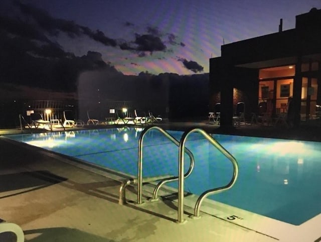 pool at dusk with a patio area