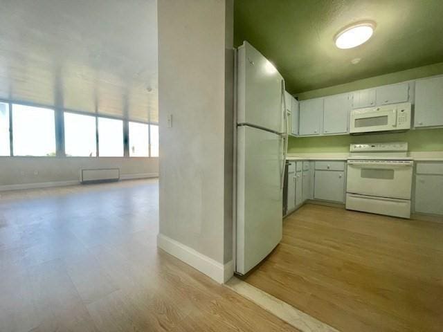 kitchen with light hardwood / wood-style flooring, white cabinets, and white appliances