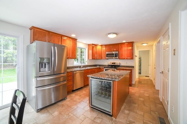 10 Morgan Cir, Holden, MA 01520 - kitchen with stainless steel appliances, dark stone counters, a sink, a kitchen island, and brown cabinetry